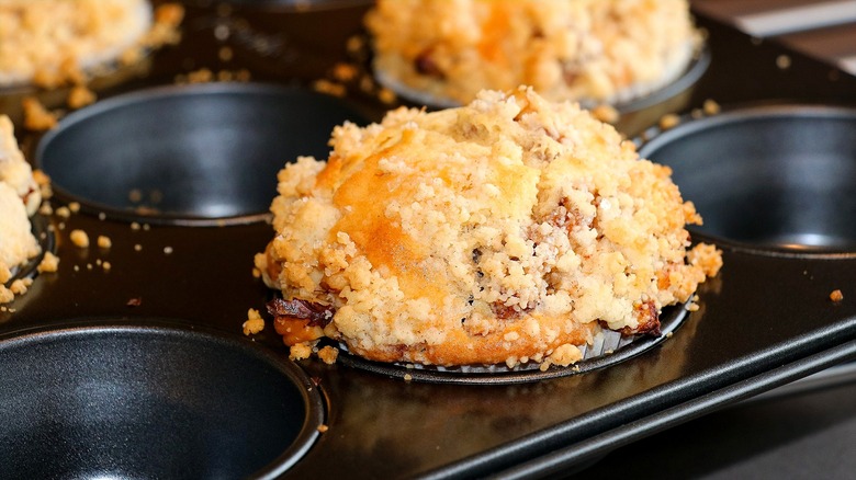 Fully baked muffins with a crumb topping in every other muffin cup