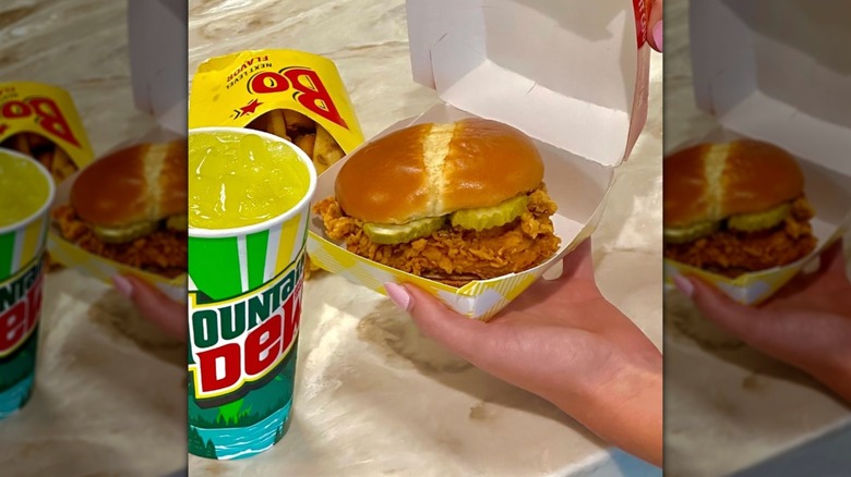 Chicken sandwich from Bojangles in paper box next to french fries and drink on counter.