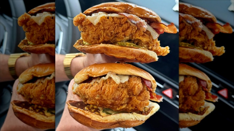 Two chicken sandwiches from Popeyes held one above the other in a car.