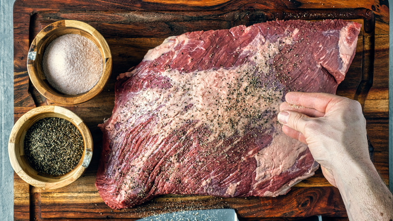 A person seasoning a cut of beef