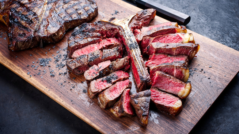 A close-up of a bistecca alla fiorentina on a wood cutting board.