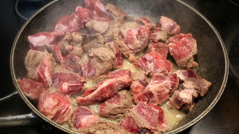 Stew beef browning in a hot skillet.