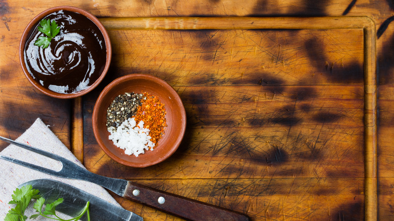 Black garlic sauce and herbs on a wooden cutting board