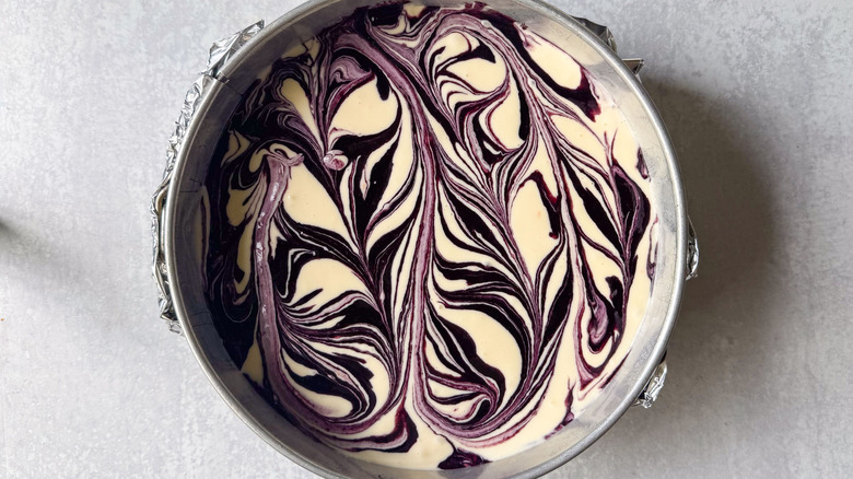 Marbled blackberry cheesecake batter in springform pan