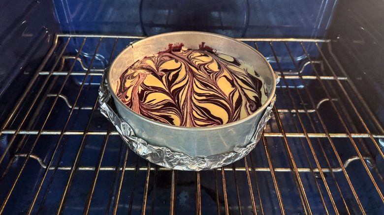 Marbled blackberry cheesecake in springform pan in oven