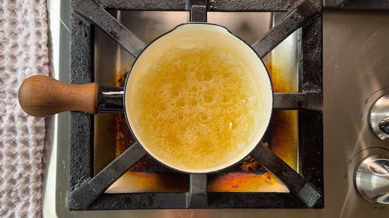 Sugar syrup boiling in saucepan on stovetop