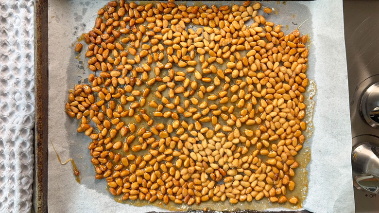 Baked candied pine nuts on parchment-lined baking sheet