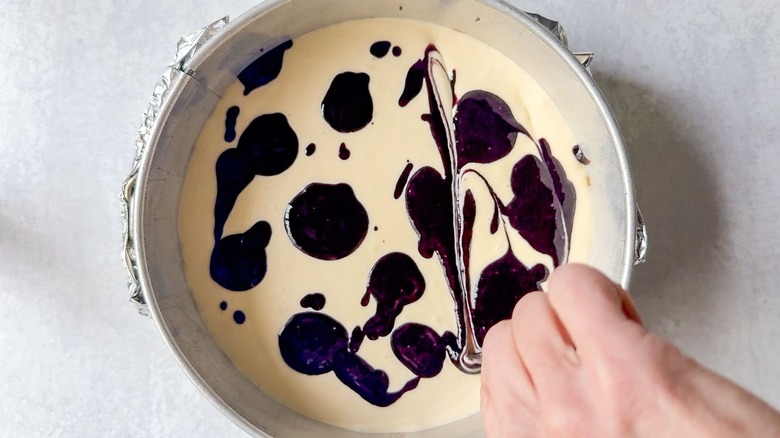 Marbling blackberry puree into cheesecake batter in springform pan