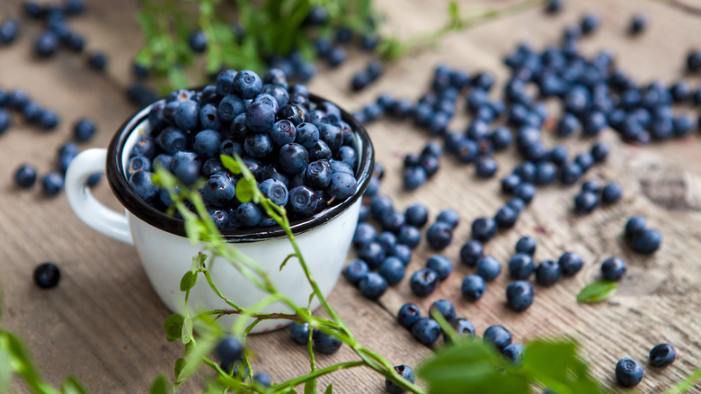 Blueberries scattered on a wooden table.