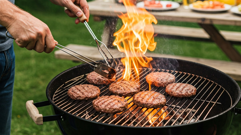 A man grilling burgers on a charcoal grill.