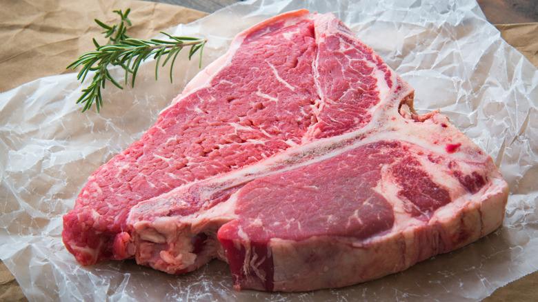 An uncooked porterhouse steak atop a piece of butcher paper.