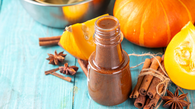 A bottle of pumpkin spice syrup with raw ingredients splayed behind it