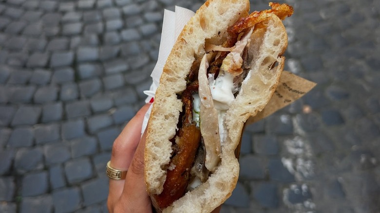 A person holding a porchetta sandwich from La Vita è un Mozzico in Rome