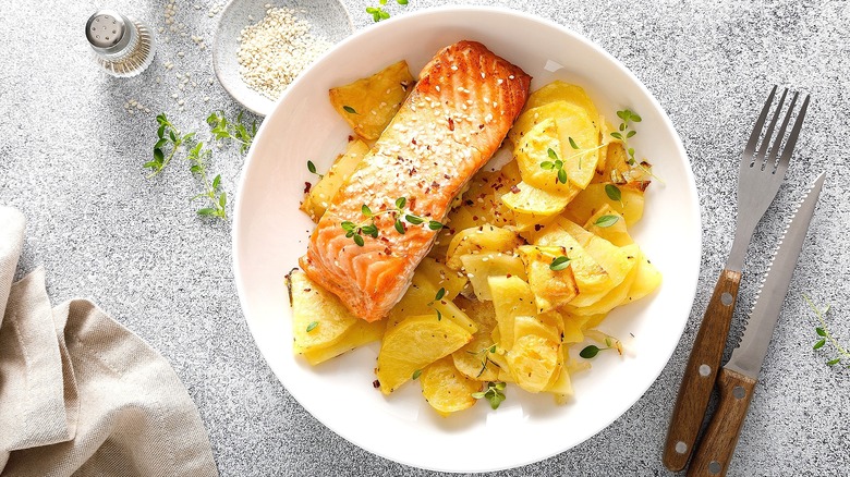 A piece of oven-baked salmon with scalloped potatoes on a white plate