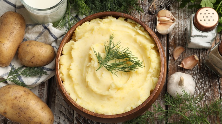 Mashed potatoes in a wooden bowl topped with herbs