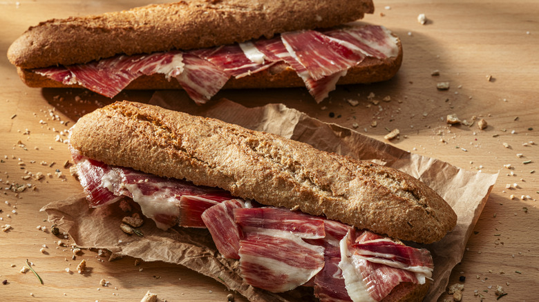 Two iberico ham subs on a wooden surface.