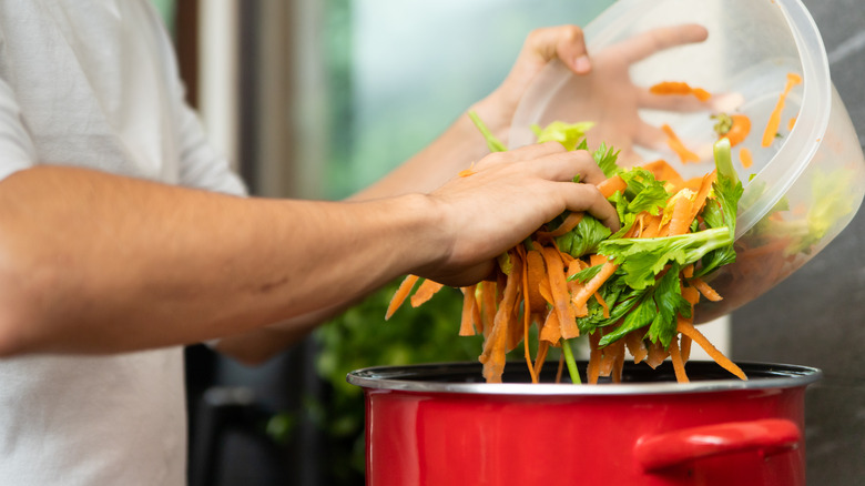 A young man makes vegetable soup or broth, out of vegetable scraps