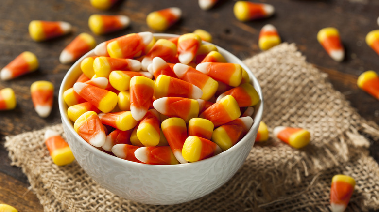 A bowl on a table filled with candy corn.