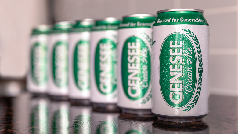 Six cans of Genesee Cream Ale lined up on a reflective surface