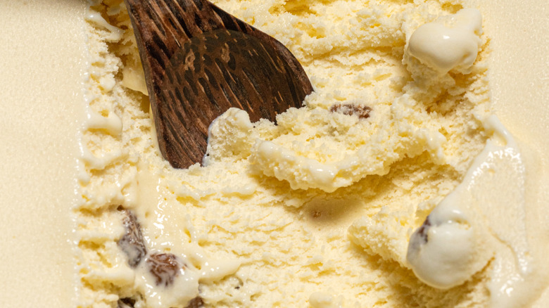 Carton of rum raisin ice cream and wooden spoon