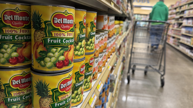 Cans of fruit cocktail in grocery store aisle