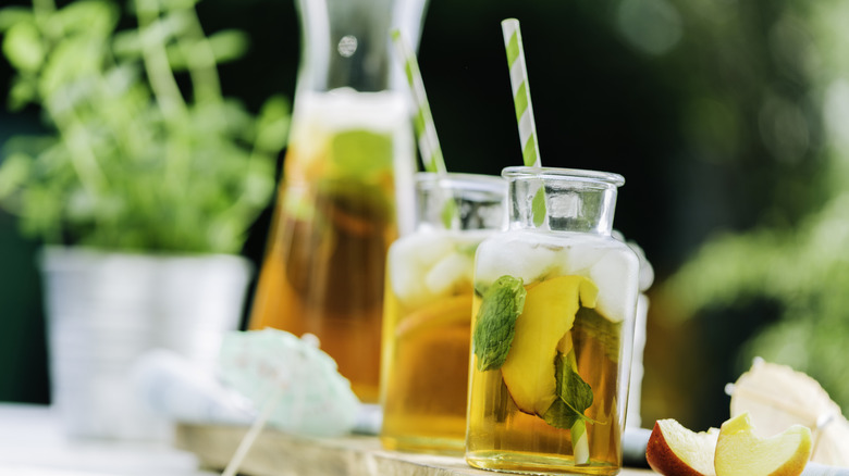 Iced tea carafe and glass with fresh peach slices.