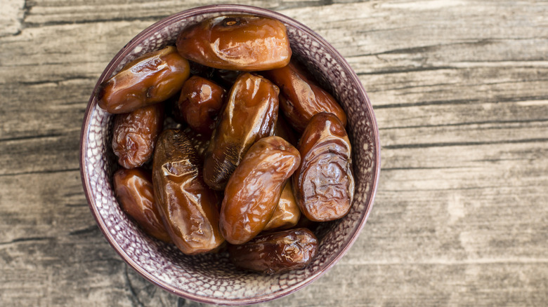 A bowl of dates on a wooden surface