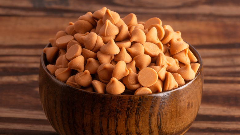 A wooden bowl full of caramel colored chips for baking.