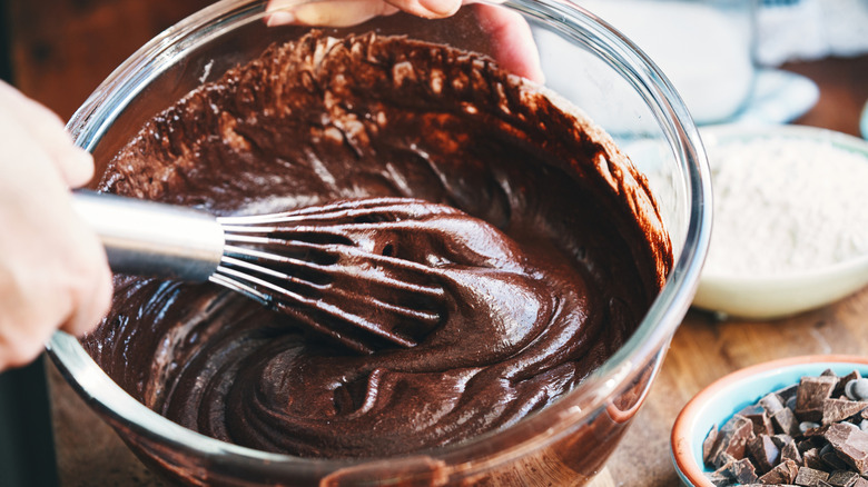 A person's hands are seen stirring brownie mix from a high angle