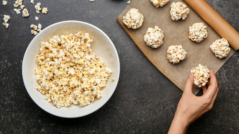 Bowl of popcorn next to a baking sheet full of popcorn balls.