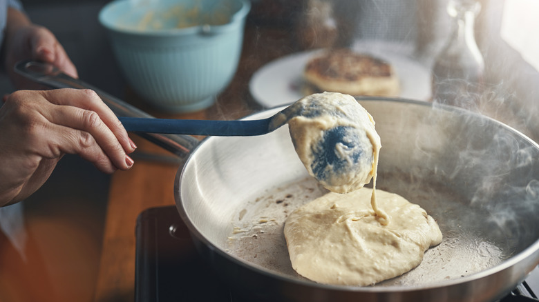 Someone ladling pancake batter into a pan