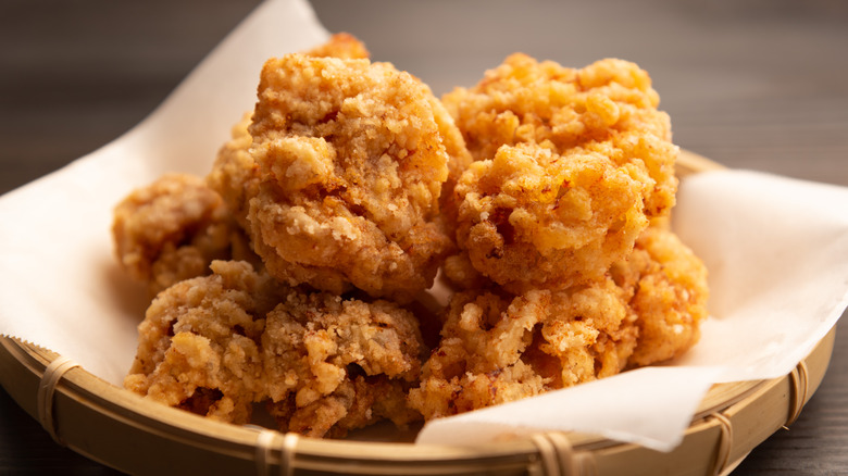 A closeup shows crispy fried chicken in a basket.