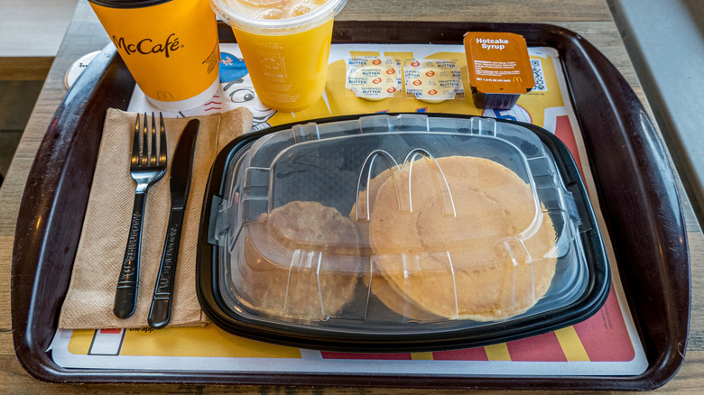 McDonald's Full Breakfast Meal with Hash Browns, Pancake, Scramble Egg, Biscuit, Sausage and a Coffee inside a McDonald's Restaurant