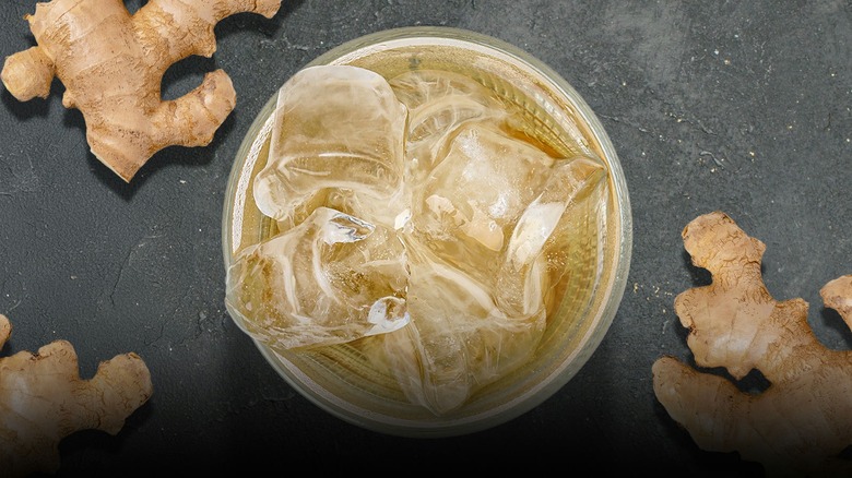 a cup of ginger ale with fresh ginger surrounding it