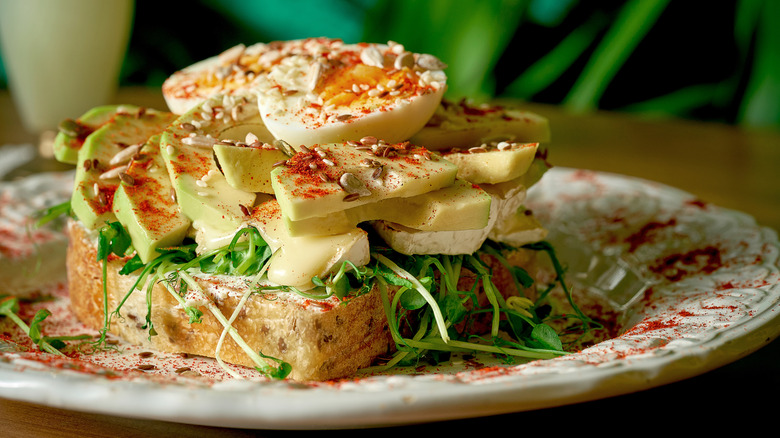 Avocado toast with Brie and greens on a plate