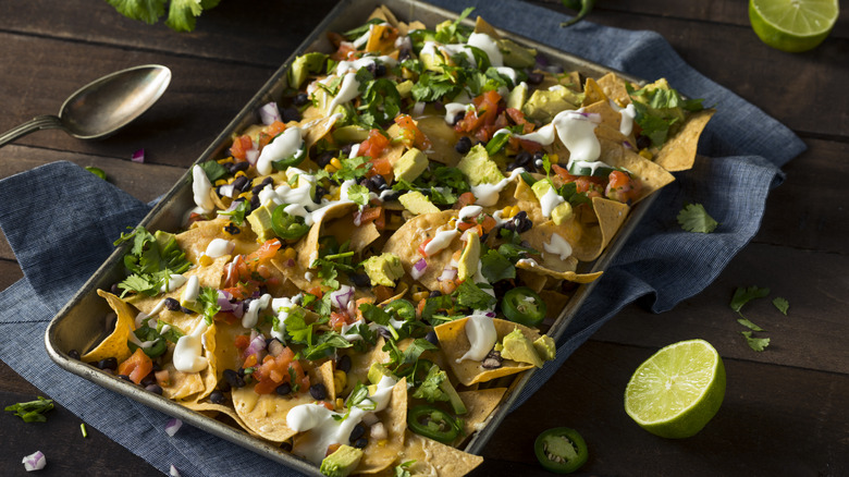A sheet pan is loaded with nachos for a group.