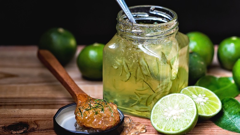Jar of lime jam with a spoon on a wooden surface