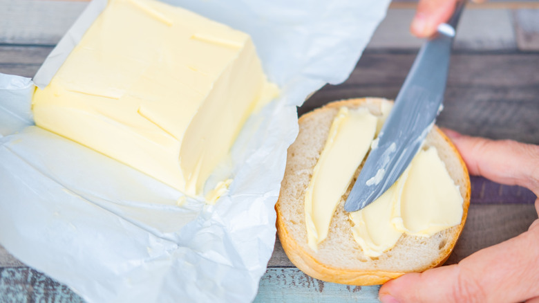 Knife spreading butter on a piece of bread