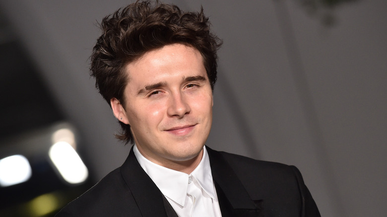 Brooklyn Beckham smiling while wearing a suit