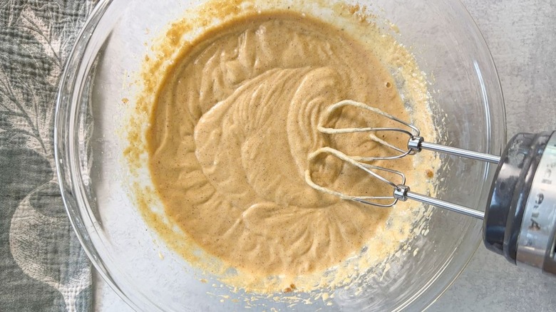 Mixing brown butter bourbon loaf cake batter with hand mixer in glass bowl