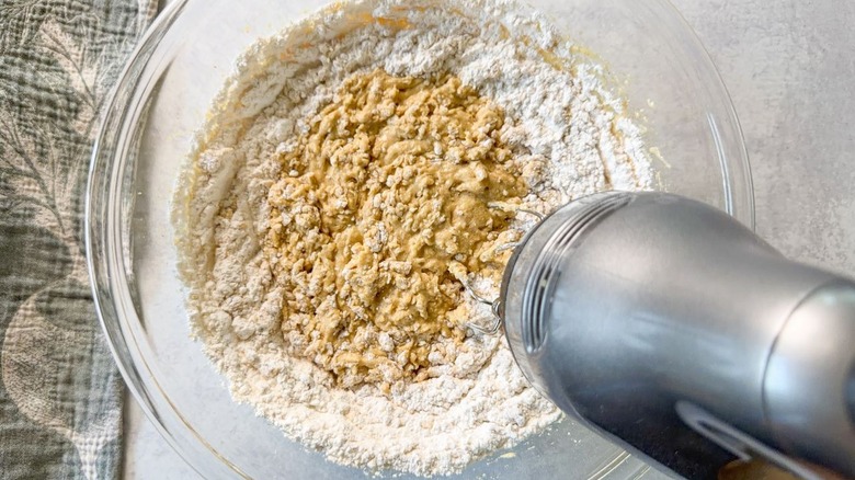 Mixing brown butter bourbon loaf cake batter with hand mixer in glass bowl