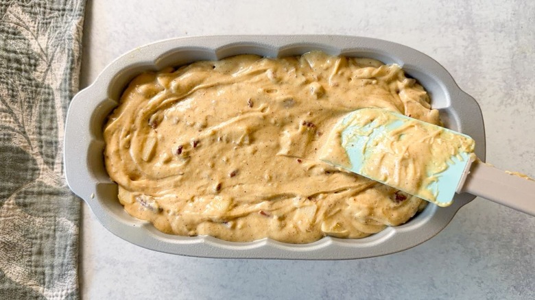 Spreading brown butter bourbon loaf cake batter into loaf pan with rubber spatula