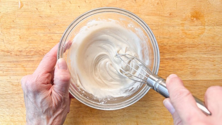 Mixing brown butter bourbon loaf cake glaze in glass bowl with whisk