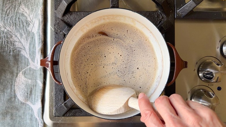 Stirring brown butter in saucepan on stovetop with wooden spoon