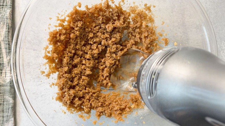 Creaming together brown butter and brown sugar in glass bowl with hand-held mixer