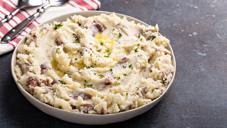 Chunky mashed potatoes in bowl with butter. 