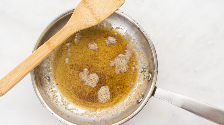 Brown butter in a skillet with a wooden spoon resting on top.