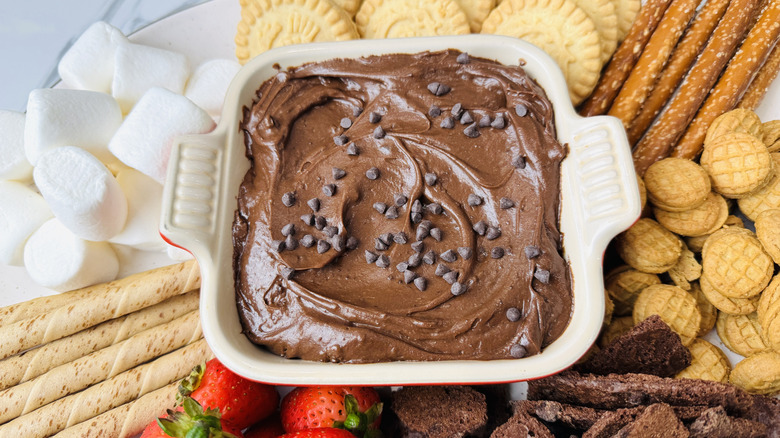 Brownie batter dip in serving dish surrounded by various dippers