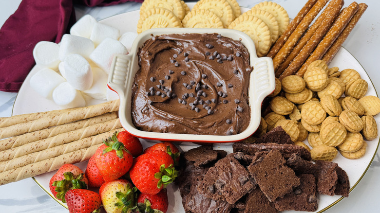 Brownie batter dip in serving dish surrounded by various dippers