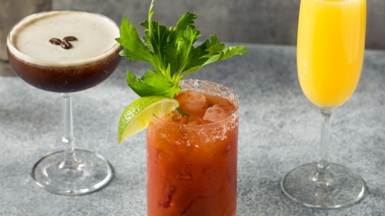 An espresso martini, a Bloody Mary, and a mimosa on a gray surface